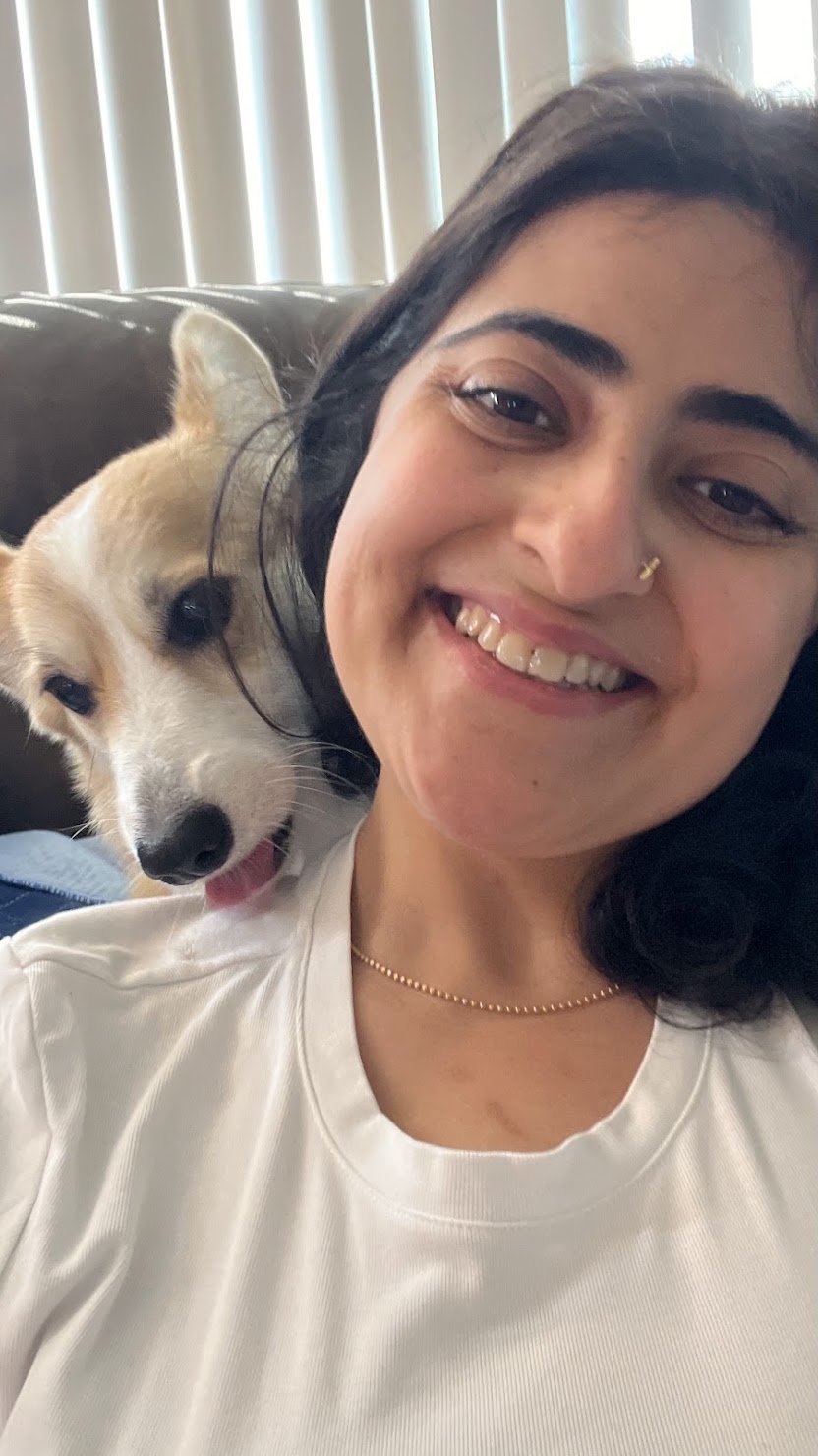 Corgi nuzzling into Ghazal's shoulder